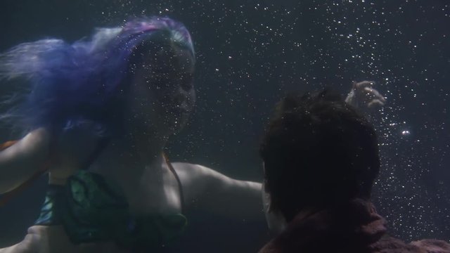 Close-up of a mysterious aqua creature finding alive man underwater.