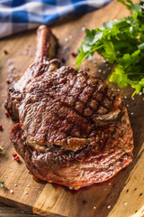 Freshly grilled tomahawk steak on slate plate with salt pepper rosemary and parsley herbs