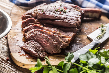 Freshly grilled tomahawk steak on slate plate with salt pepper rosemary and parsley herbs. Sliced...