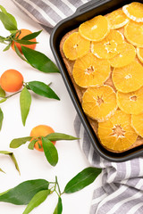 Orange-mandarin pie in baking dish on a striped linen towel