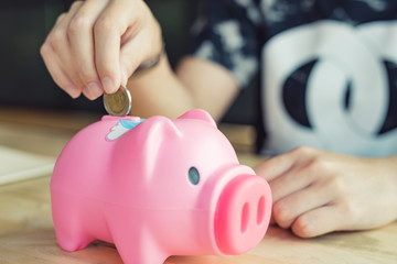 Woman Putting Coin In Piggy Bank, Indoors - Image