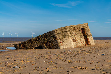North sea coast in Caister-on-Sea, Norfolk, England, UK -  with an old bunker on the beach and wind turbines in the background
