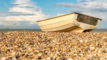 Clouds over a boat on the pebbles of Tankerton beach in Whitstable, Kent, England, UK