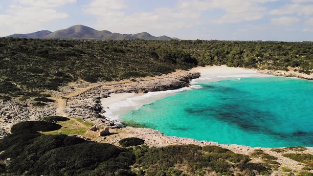 a drone shot flying to the right that shows the two empty hidden beaches at cala varques in majorca