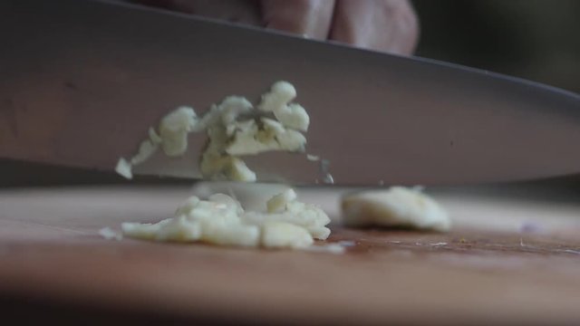 Slow motion close-up of mincing garlic cloves