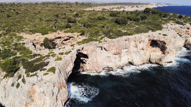 A drone shot panning around to reveal a large sea arch near cala varques in majorca