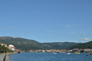Fototapeta na wymiar Boats Moored Along With Mussel Breeders In The Estuary Of The Muros Village. Nature, Architecture, History, Street Photography. August 19, 2014. Muros, Pontevedra, Galicia, Spain.