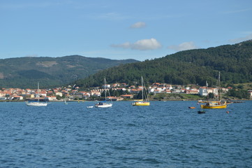 Fototapeta na wymiar Boats Moored Along With Mussel Breeders In The Estuary Of The Muros Village. Nature, Architecture, History, Street Photography. August 19, 2014. Muros, Pontevedra, Galicia, Spain.