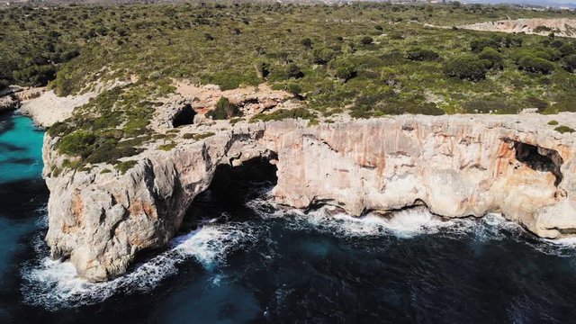 a drone shot panning around a large sea arch near cala varques in majorca