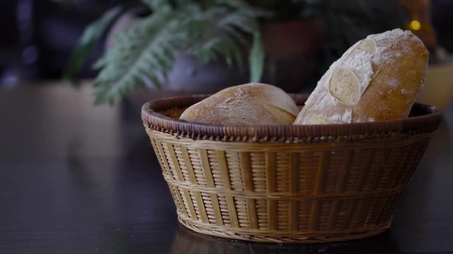 a slow zooming 4k shot of crusty golden brown sourdough bread in a basket with fern leaves in the background