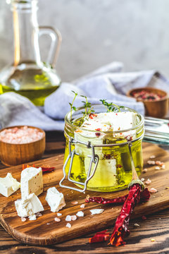 Feta cheese marinated in olive oil with fresh herbs in glass jar