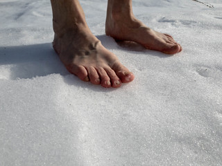 A man walks with his bare feet in the snow and ice.Barefoot in the snow