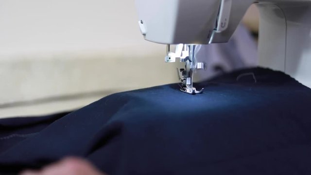 Sewing a straight line on blue fabric in slow motion.