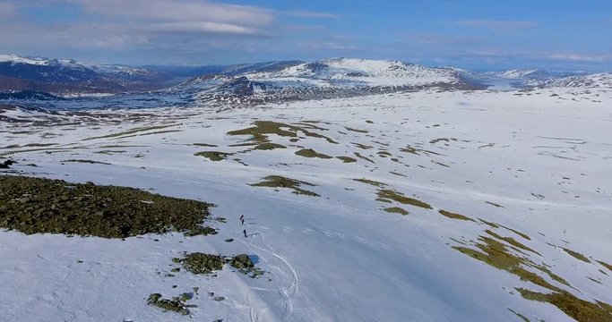 Aerial view of three skiers (snowboard, telemark skies and alpine skies) freeriding down a mountainside in Jotunheimen in Norway.