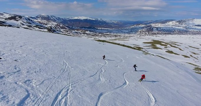 Randonee skiers and snowboarder freeriding a mointain side in Jotunheimen in Norway.