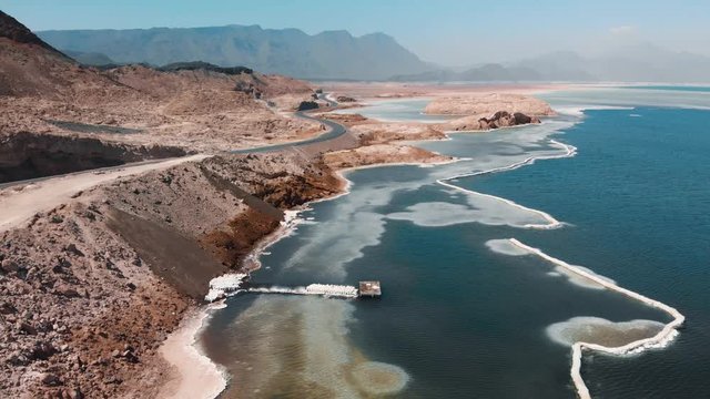 Aerial of Salt Lake Assal Djibouti Africa Volcanic Area - Crystal Blue Water and Rocky Hills Desert - Cinematic Footage 4K Forward Reveal Opener Shot