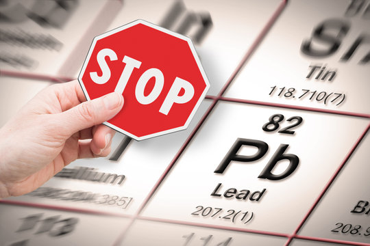 Stop heavy metals - Concept image with hand holding a stop sign against a Lead chemical element with the Mendeleev periodic table on background