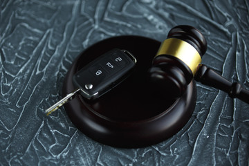 Close-up Of Gavel And Car Key On Sounding Block Against Grey