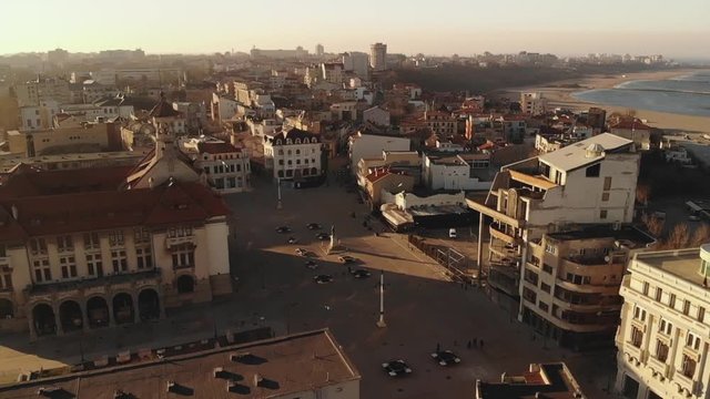 Pan aerial shot of Old Town Constanta City and harbor, Romania, Europe. Shot in spring during sunset and Golden Hour, revealing the Black Sea, History Museum and architecture while seagulls fly