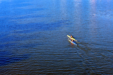 Two guys paddle the river on a kayak in river at cold season. View from above. Back view