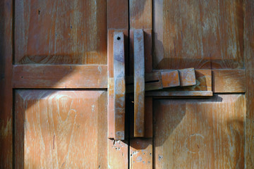 Old wooden door latch on closing wood gate with morning sunlight