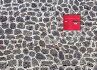 Boîte aux lettres rouge incrustée dans mur en moellons 