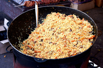 Cooking armenian pilaf dish in outdoor. pilaf in a cauldron, street food