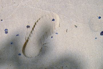 One left footstep on beach sand with sunlight and shadow