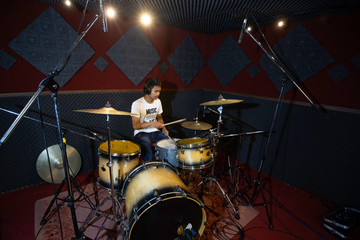 Young musicians are drumming to record the sound in the recording room.