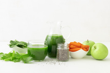 Vegetable smoothie, healthy organic juice made from celery, green apples, leaves of spinach and young carrot. Big pitcher and small glass of green juice, jar with chia seeds. Free space for your text.