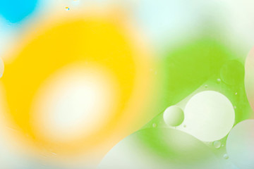 Abstract gentle blurred background. The texture of the liquid with circles and drops of green, yellow, blue and white. Cropped shooting, macro, horizontal, nobody, free space for text.