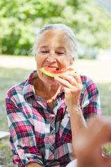 Senior Frau isst eine Wassermelone im Park