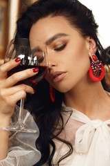 sensual woman with dark hair in elegant clothes and earrings sitting in restaurant, eating delicious italian pasta