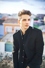 Portrait of handsome young man in black posing on the street