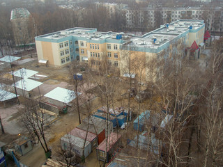 Fototapeta na wymiar View from the height of the five-storey building among the bare trees and metal containers