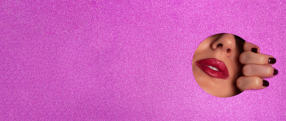 Female fingers, nose and lips with red lipstick through glitter violet paper. Business card of artist, beauty concept. Ready to new year party. Cosmetics sale. Beauty salon advertising banner