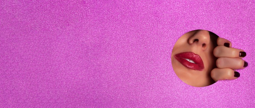 Female fingers, nose and lips with red lipstick through glitter violet paper. Business card of artist, beauty concept. Ready to new year party. Cosmetics sale. Beauty salon advertising banner