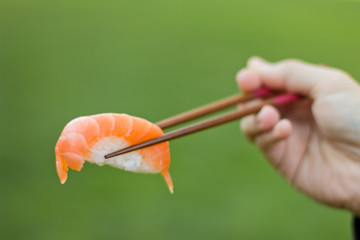 Sushi ready to eat on chopsticks outdoors