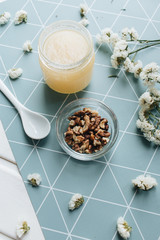 Walnuts, honey and white flowers on table