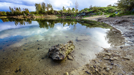 Sandy hills. Lake in the Sandy canyon. Warm colors background. Yellow sandstone textured mountain, white thin sand dune, bright sky. Sunshine landscape