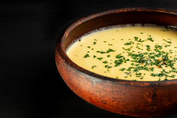 Roasted pumpkin soup with cream on black wooden background.