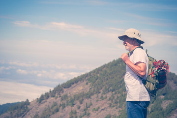 Retired lifestyle mature man with backpack traveling and enjoying the outdoor leisure activity on the top of a mountain looking the sky and the landscape with satisfaction