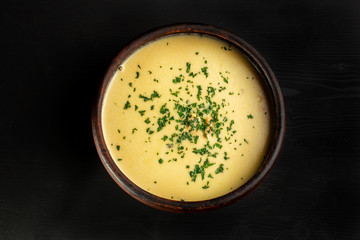 Roasted pumpkin soup with cream on black wooden background.