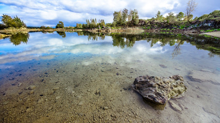 Sandy hills. Lake in the Sandy canyon. Warm colors background. Yellow sandstone textured mountain, white thin sand dune, bright sky. Sunshine landscape