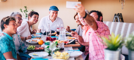 Group of mixed ages generations friends enjoy and have fun together at the table eating food and drinking in home or restaurant leisure activity - celebrate and be happy in family