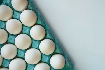 many white eggs lie in a bright turquoise blue tray on a light background with free space on the right