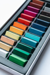 Set of bright drawing crayons, pieces of chalk in box