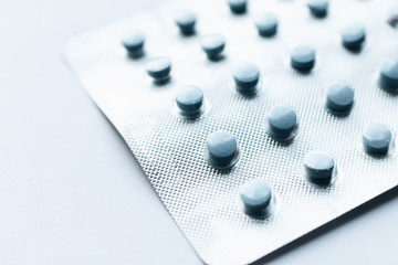 Blister with blue pills on grey background