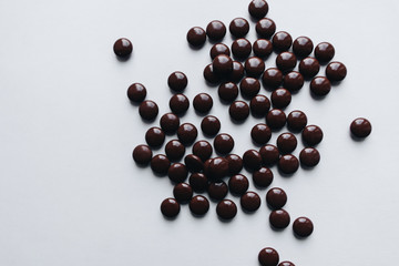 Flat lay of delicious sweet chocolate drops on white background