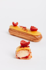 Set of delicious eclairs with yellow glaze and raspberries